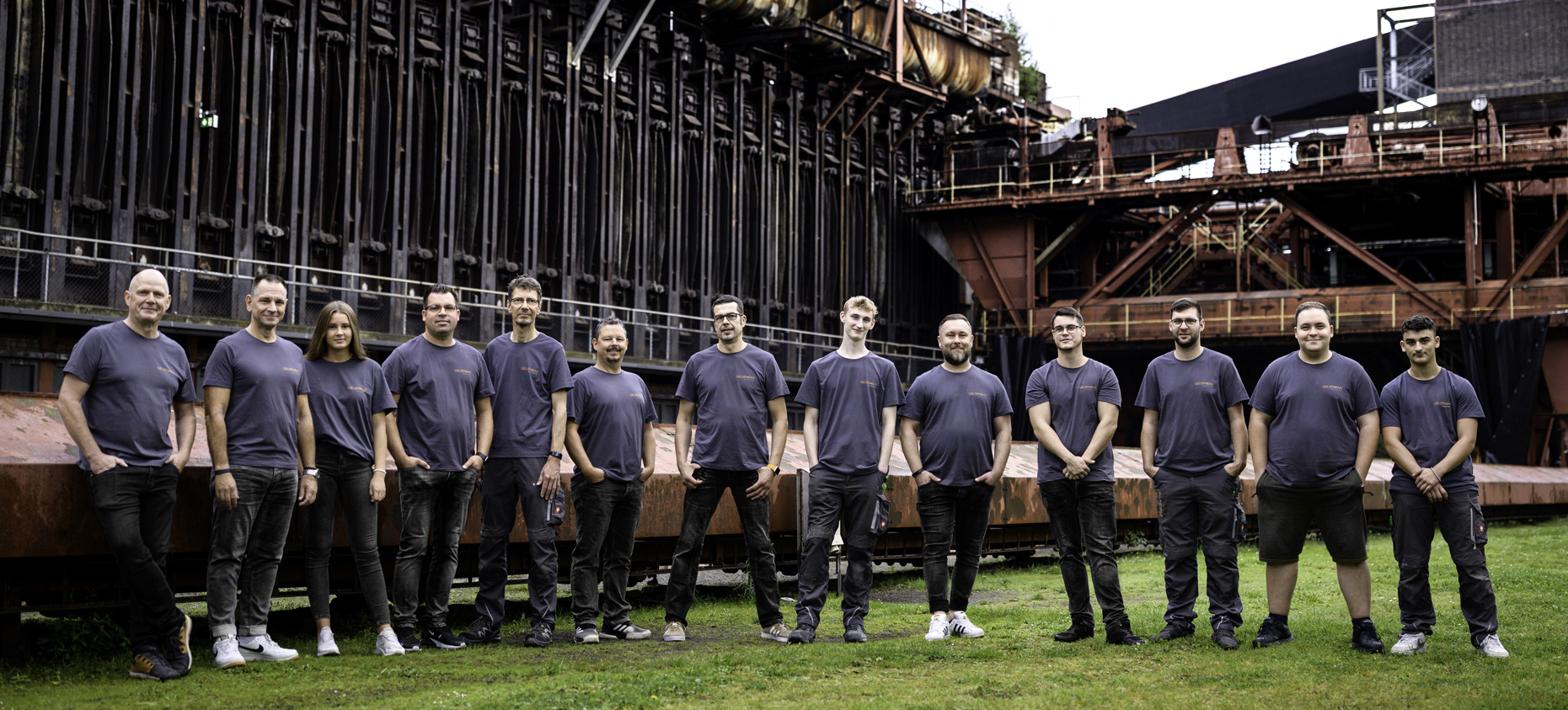 Zu sehen ist ein Gruppenfoto der Techniker von der Gelsenbad GmbH auf einem Rasen, direkt angrenzend zum Industriegebiet.